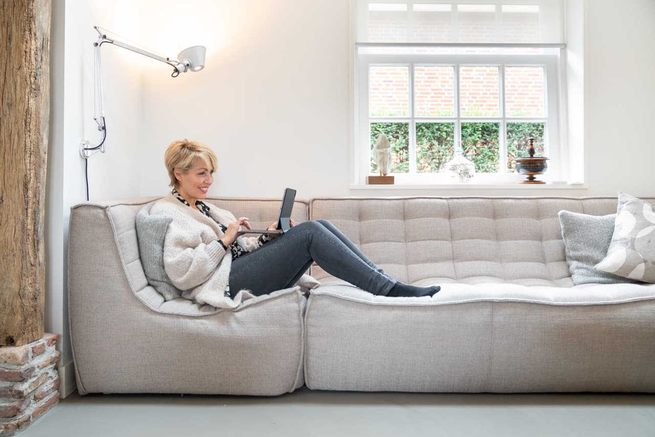 Vrouw relaxed op bank met iPad.