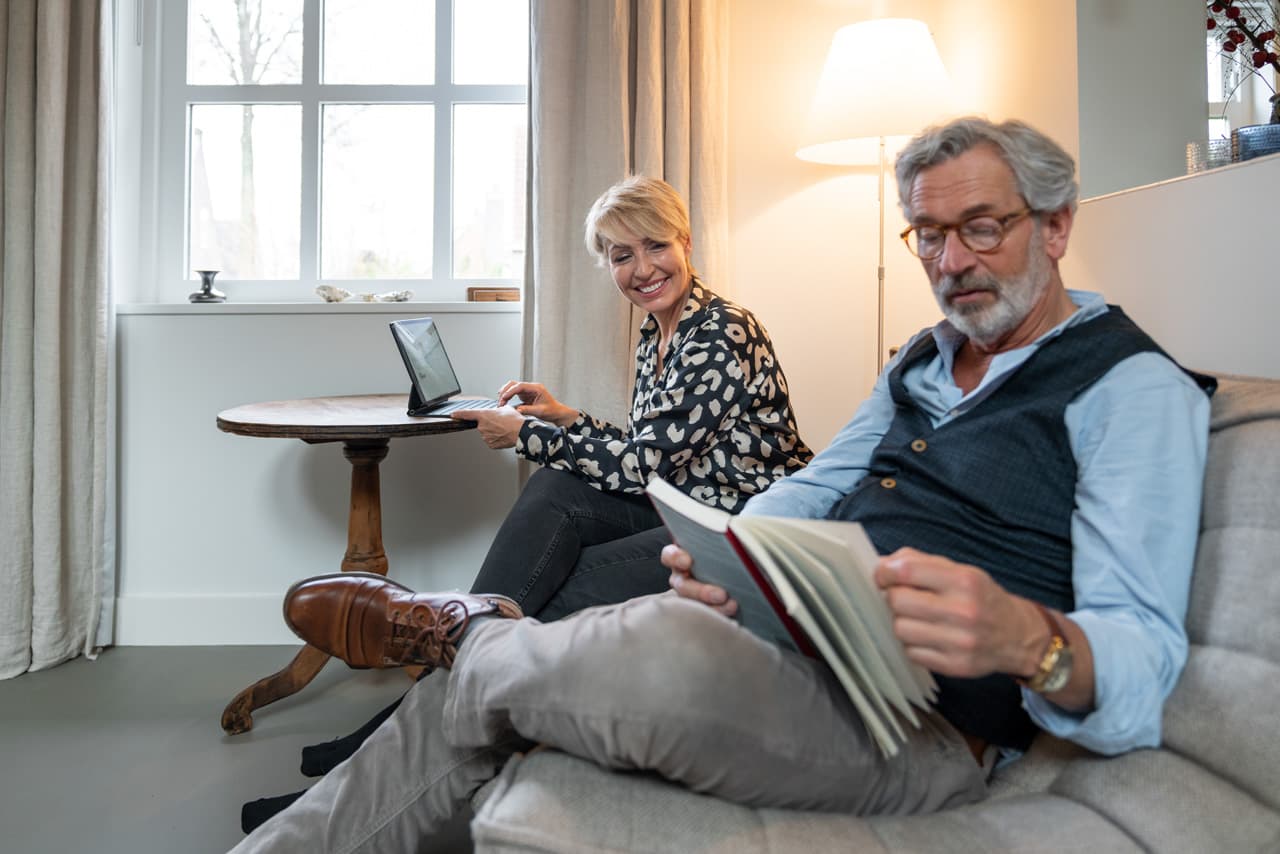 Koppel op bank, vrouw iPad, man boek.