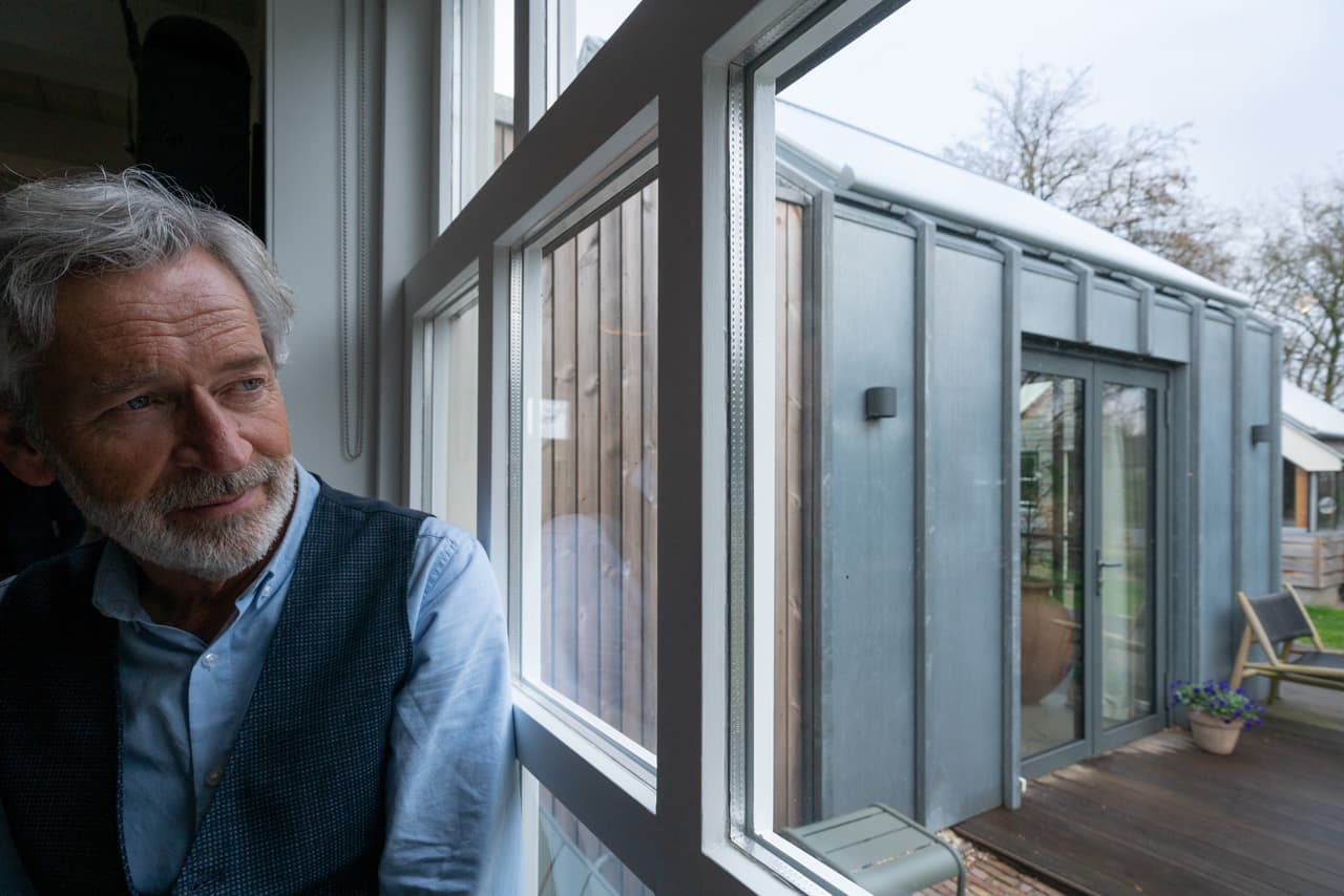 Man kijkt door raam naar buiten.