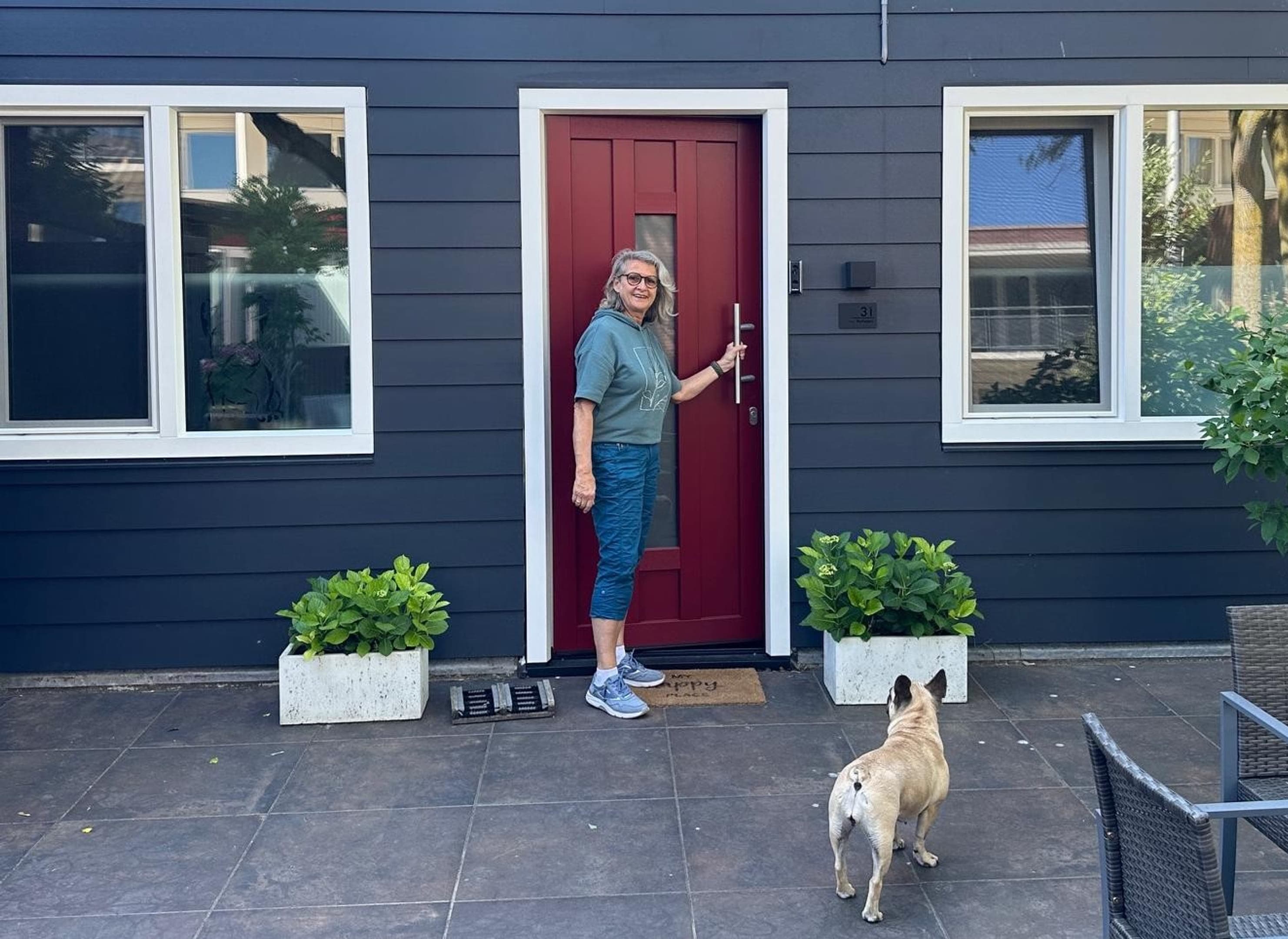 Vrouw met hond voor de deur van jaar huis, er zijn nieuwe kozijnen en een nieuwe deur aangebracht