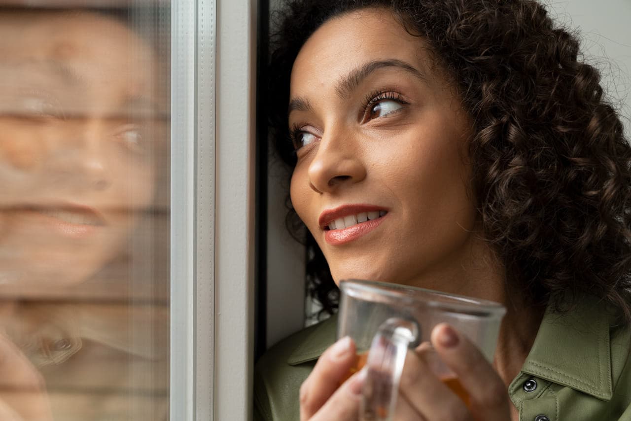 Vrouw close-up kijkt door tuindeuren naar buiten, spiegelbeeld.