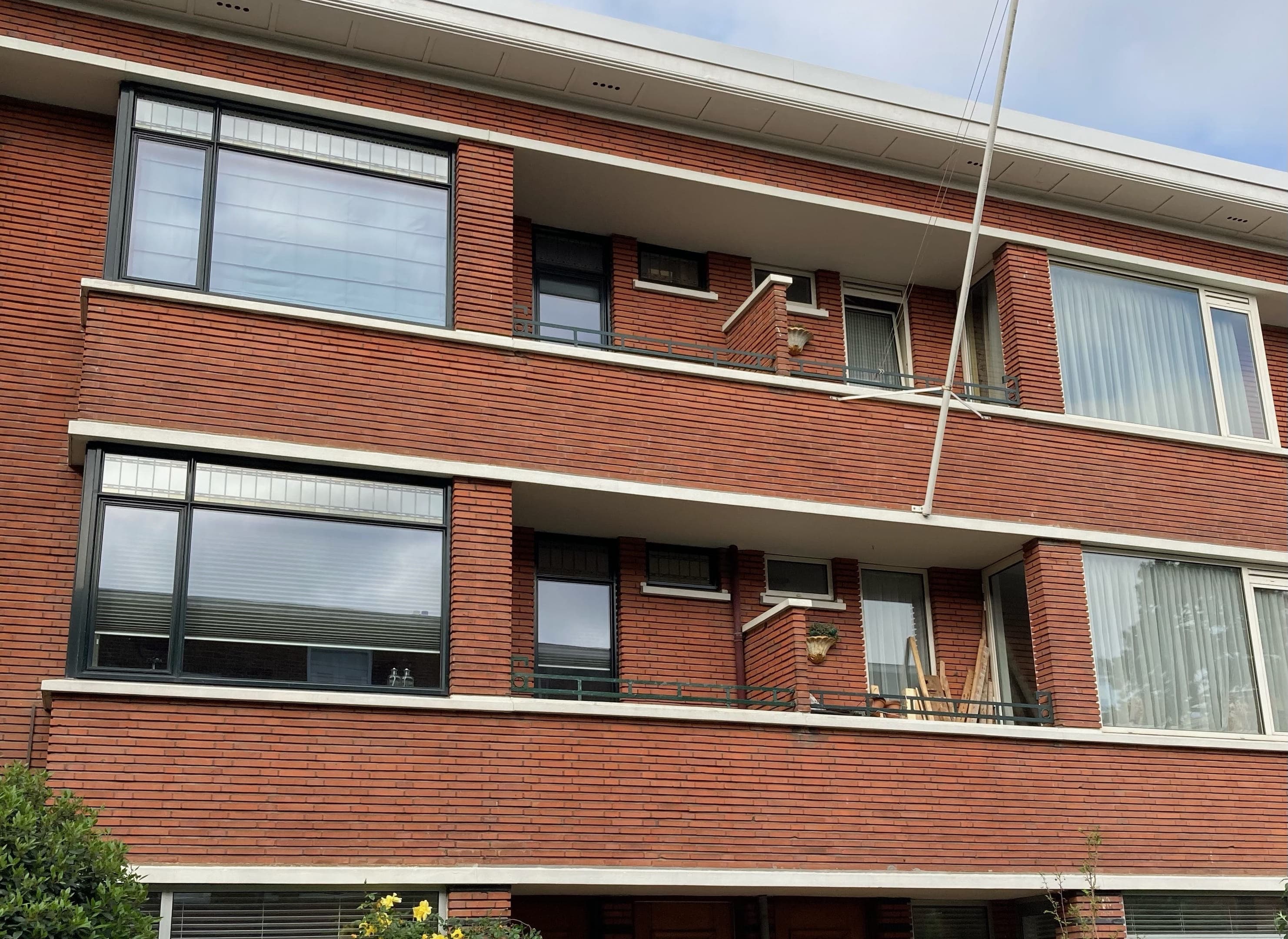 Foto van een karakteristiek ouder kleinschalig appartementengebouw in rode baksteen, met stenen balkons.