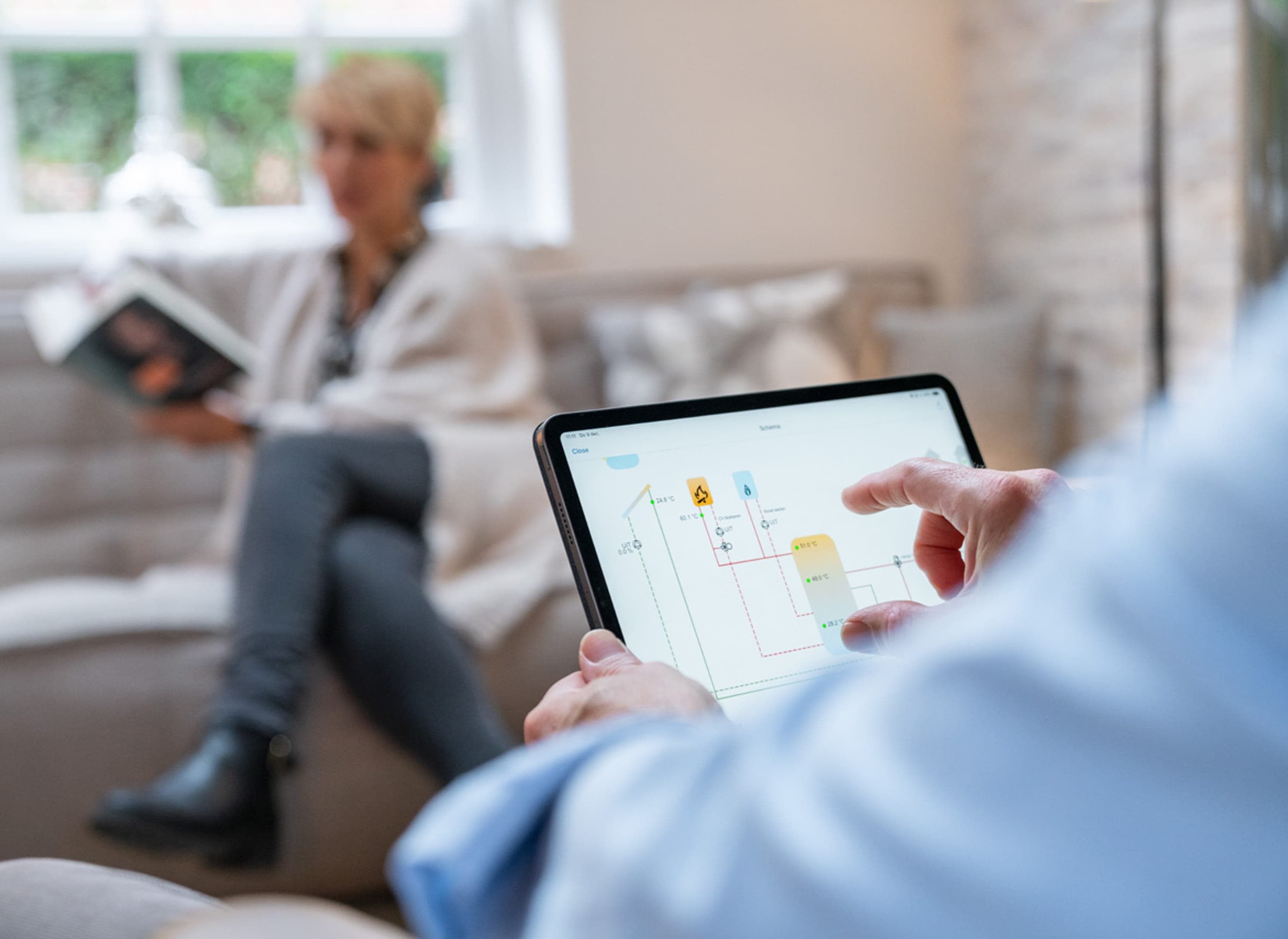 Scherm in beeld, hand man, vrouw vaag op achtergrond.