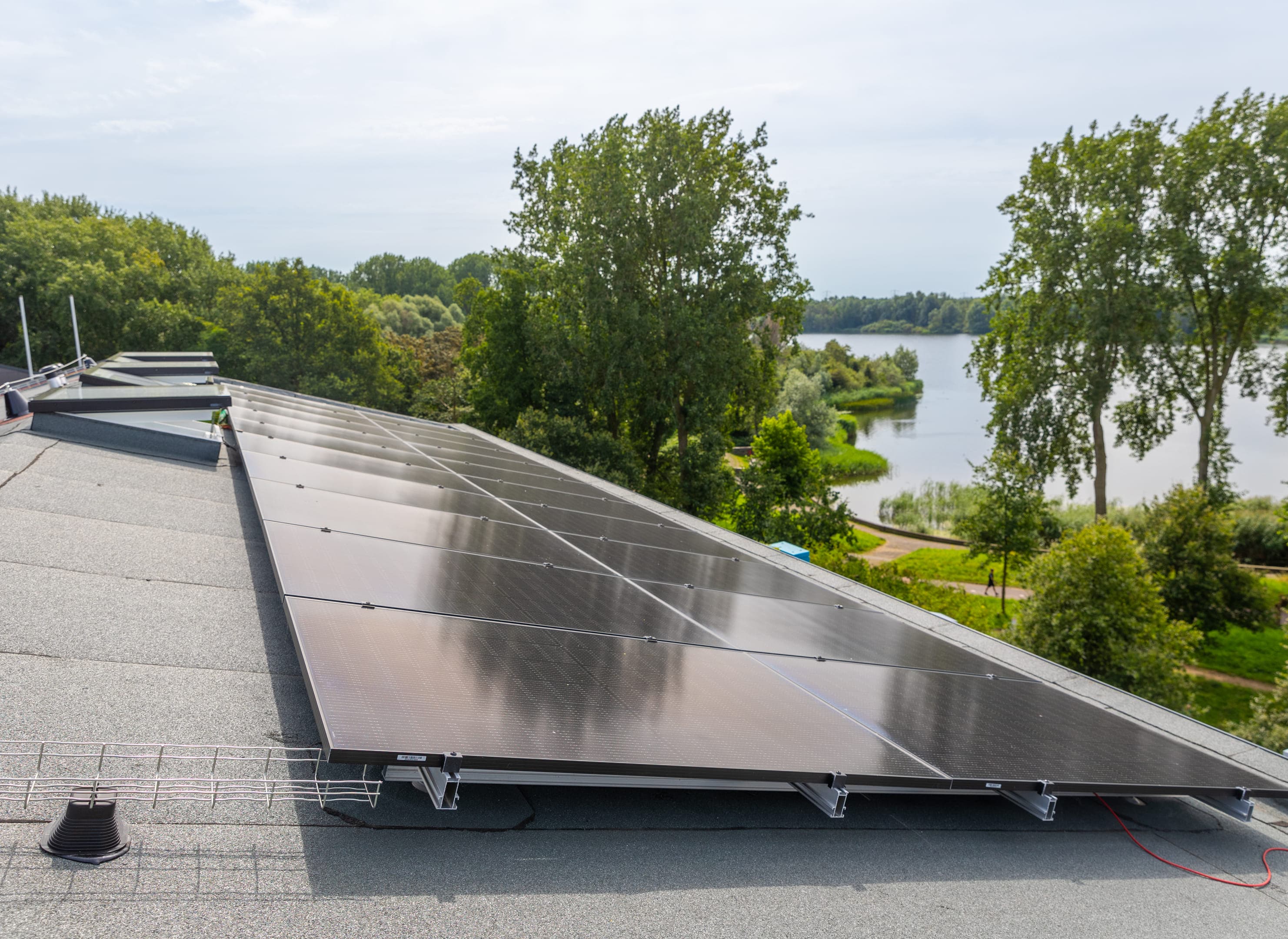 Zonnepanelen op een dak van een woning, aan het water rechts.