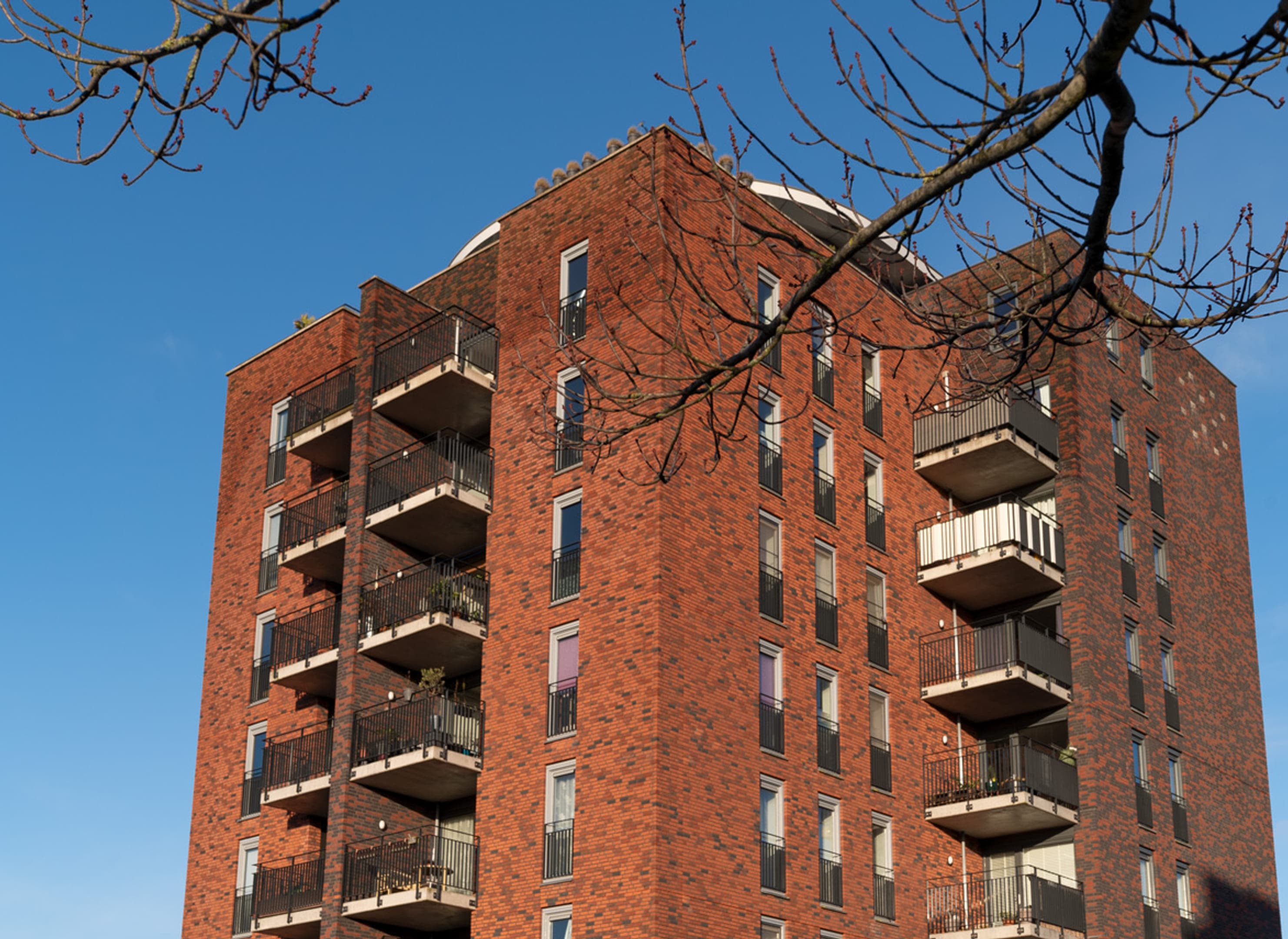 Groot vierkant modern appartementengebouw in rood baksteen, top aanzicht.