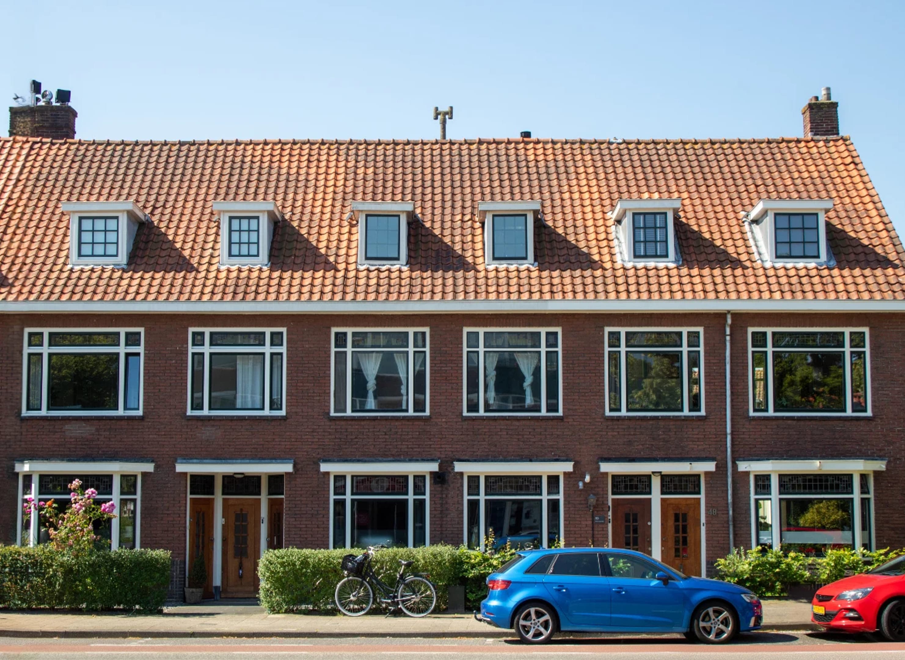 Vooraanzicht van een serie rijtjeshuizen met rode dakpannen.