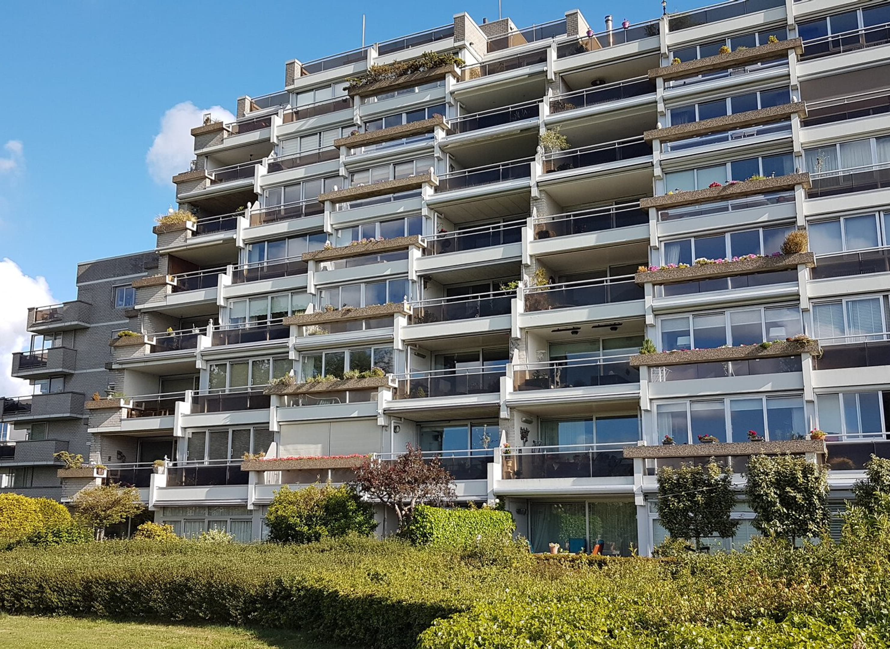 Foto van een groot, trapsgewijs aflopend appartementengebouw met balkons.
