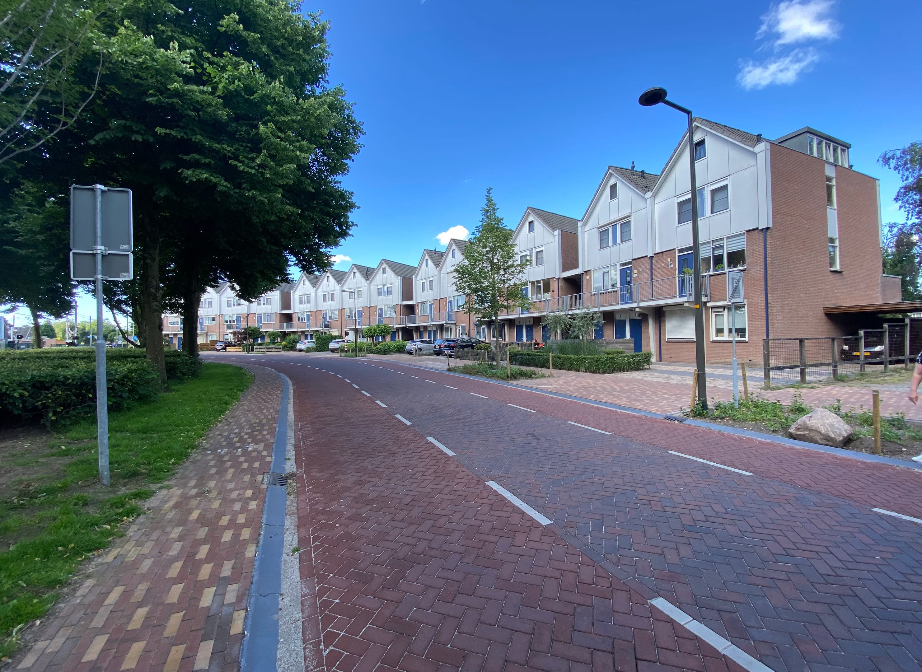 Straat met rijtjeshuizen met lichtbruine baksteen en witte fronten