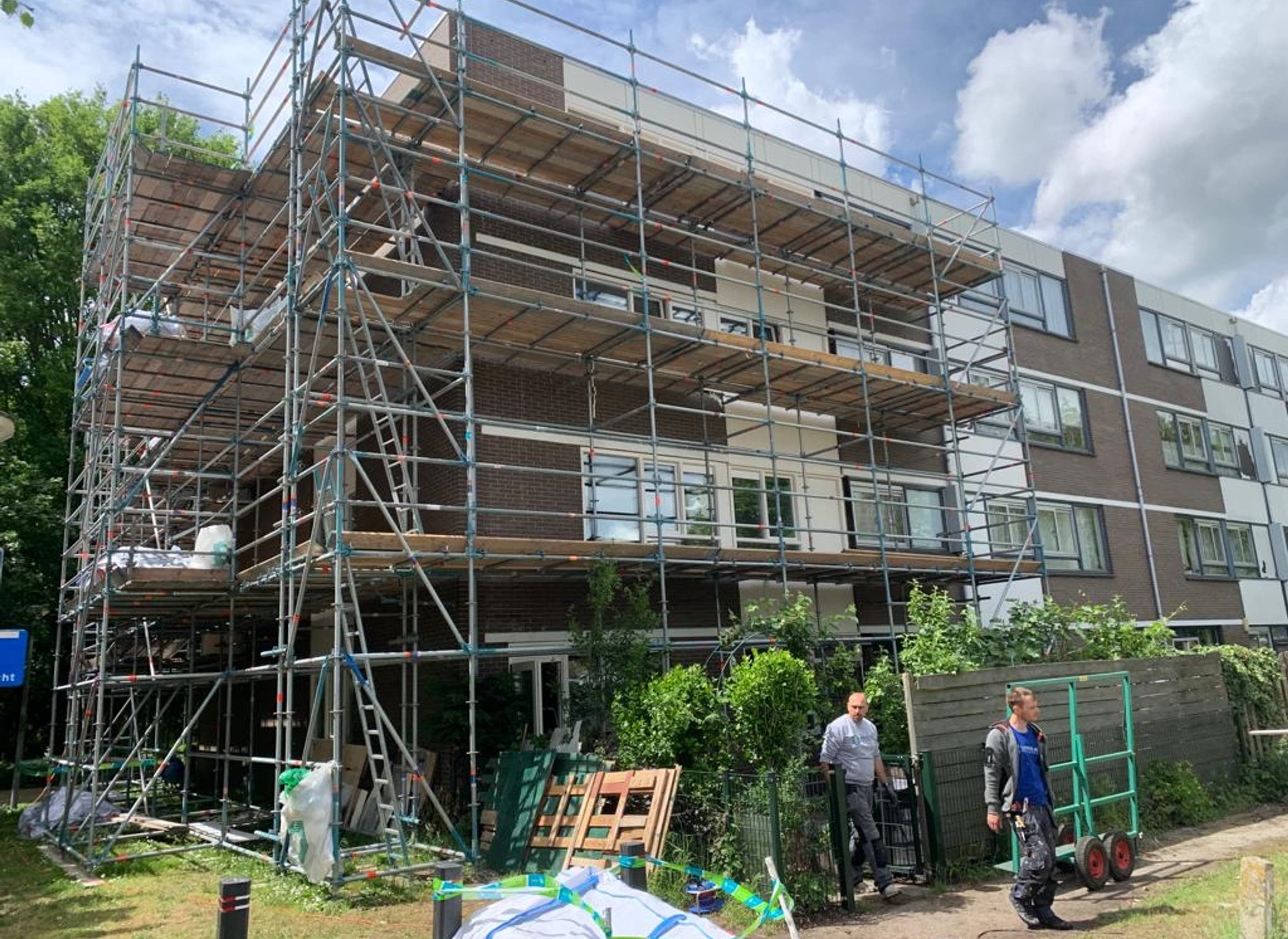 Appartementengebouw in de steigers met werklui ervoor